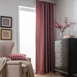 Red and white checkered curtains with tassels and matching pillow in a cozy living room