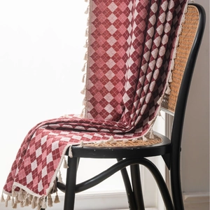 Retro red and white checkered blanket with tassels draped on a vintage wooden chair