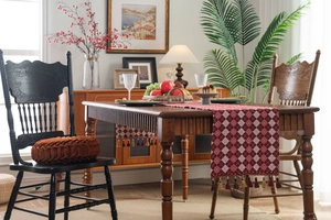 Detail of red and white lattice table runner with decorative tassels on wooden table