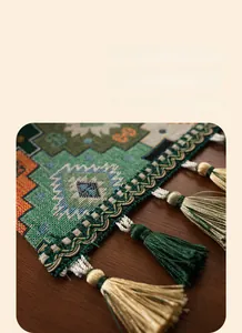 Detailed view of bohemian jacquard table runner with green geometric patterns and tassels