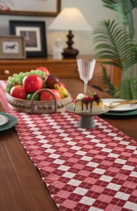 Detailed texture of red and white plaid table runner with fringe on a wooden table