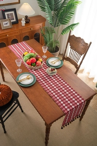 Close-up of red and white checkered table runner with elegant fringe tassels for dining decor