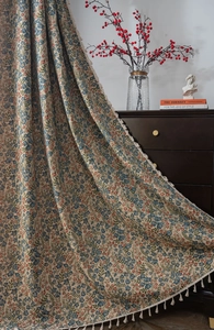 Detailed view of floral jacquard curtain fabric with vintage blue flowers and fringe