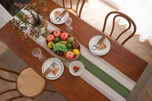 Dettaglio del runner da tavola intrecciato in tessuto beige con strisce verdi e pizzo