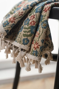 Detail of floral jacquard fabric with rustic ethnic pattern and beige cotton fringe tassels