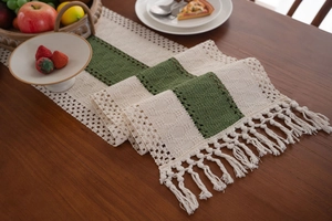 Dettaglio del runner da tavola intrecciato verde salvia e beige con nappe stile boho