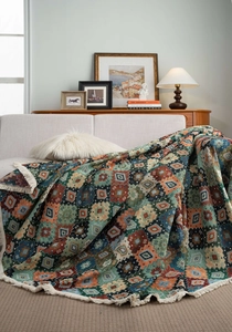 Detail of bohemian geometric pattern throw blanket with white cotton fringe on sofa