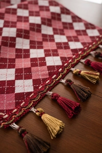 Macro shot of red and white jacquard checkered table runner with detailed tassels