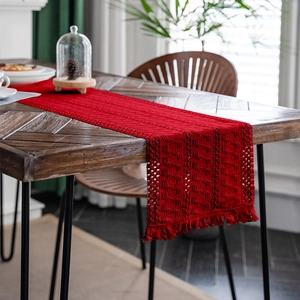 Dettaglio del runner da tavolo rosso all'uncinetto con motivi geometrici e nappe a frangia