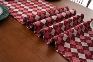 Detail of red and white checkered table runner with jacquard texture on wooden table