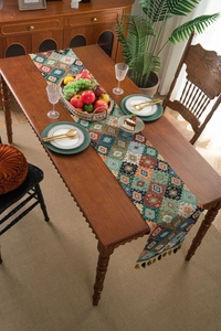Close-up of bohemian woven table runner with geometric jacquard patterns and tassels