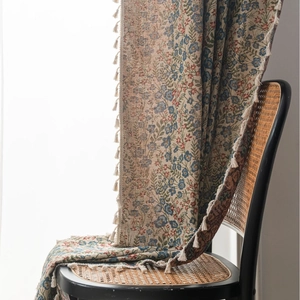 Floral jacquard curtain with blue flowers and white tassels draped on a rattan chair
