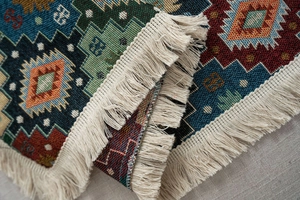 Close-up of thick jacquard sofa throw featuring colorful diamond patterns and fringe trim