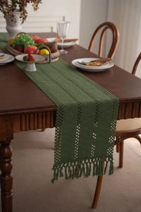 Dettaglio del runner da tavola verde intrecciato a mano con nappe e motivi all'uncinetto