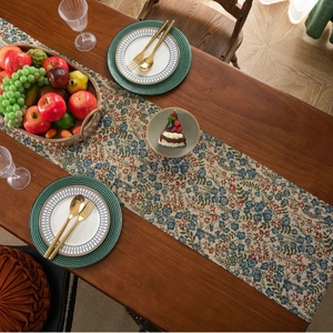 Floral jacquard table runner with blue flowers and red berries on a wooden table