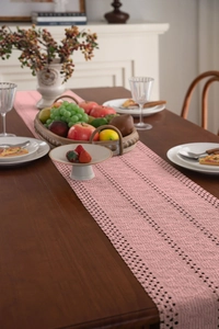 Dettaglio del runner da tavola rosa antico all'uncinetto con trama in cotone intrecciato