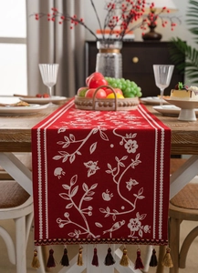 Detail of red floral table runner with intricate white jacquard patterns and tassels