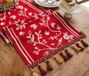 Detail of red table runner with white floral jacquard and multi-color tassel fringe