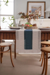 Dettaglio del runner da tavola a righe blu scuro con pizzo crema e nappe decorative