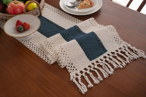 Dettaglio del runner da tavolo intrecciato con strisce blu navy e crema e nappe