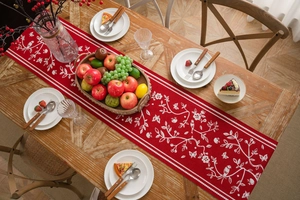 Detail of red festive table runner with white bird and floral embroidery on a wooden table