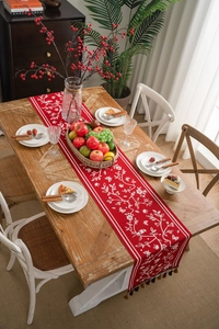 Macro detail of red festive table runner with floral embroidery and tassel fringe
