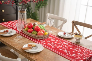 Close-up of red table runner with white bird and flower jacquard on a wooden table