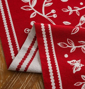 Detail of red jacquard table runner with bird and branch patterns and thick woven texture