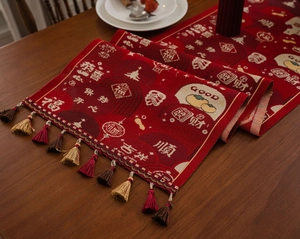 Detail of red Chinese New Year table runner featuring golden tassels and festive jacquard