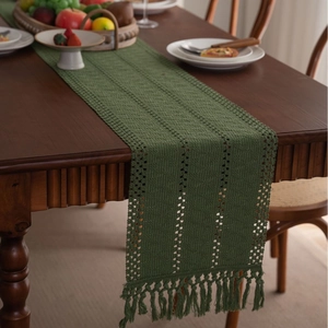 Runner da tavola in crochet traforato verde scuro con nappe su tavolo in legno