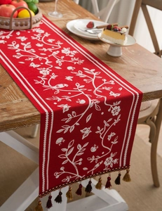 Macro detail of red table runner featuring floral jacquard patterns and elegant fringe tassels