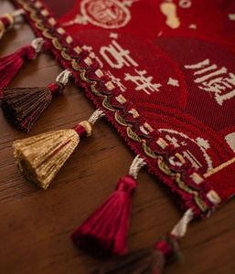 Close-up of red Chinese New Year table runner with jacquard motifs and tassel detail