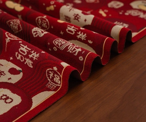 Close-up of red festive table runner with traditional gold jacquard patterns and motifs