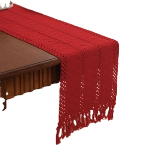 Runner da tavola geometrico all'uncinetto rosso scuro con nappe su tavolo legno
