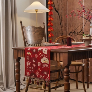Red festive table runner with traditional patterns, tassels, and auspicious greetings