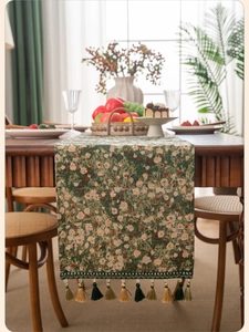 Detailed close-up of dark green floral jacquard table runner with hanging tassels