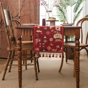 Red festive Chinese New Year table runner with jacquard patterns and tassel accents