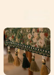 Detailed view of floral jacquard table runner with decorative green and gold tassels
