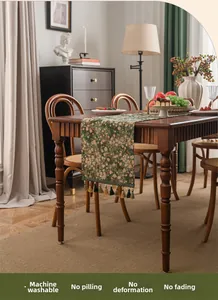 Detail of green floral table runner with tassels featuring durable and washable fabric