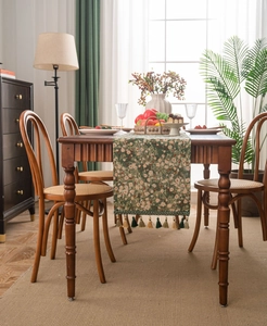 Detail of olive green floral jacquard table runner with decorative fringe tassels