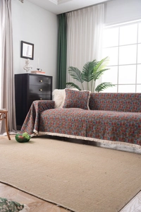 Dettaglio del copridivano bohémien colorato con motivi geometrici e dettagli di frange