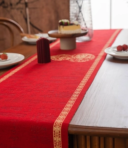 Detail van een rode feestelijke tafelloper met gouden borduursels en motieven