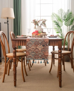 Detail of bohemian jacquard table runner with ginkgo leaf patterns and blue tassels