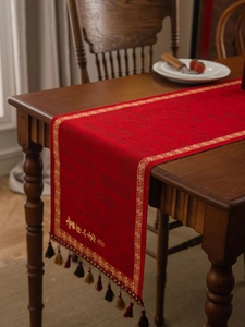 Macrodetail van de rode feestelijke tafelloper met goudborduursel en elegante kwastjes