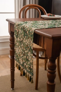 Close-up of green floral table runner with textured jacquard weave and hanging tassels