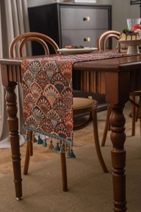 Detail of jacquard table runner featuring ginkgo leaf pattern and fringe tassels
