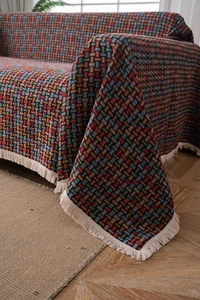 Dettaglio del copridivano jacquard a scacchi colorati con frange color bianco crema