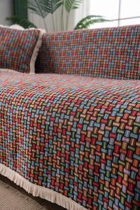 Dettaglio del copridivano bohémien verde intrecciato con motivi jacquard e frange bianche