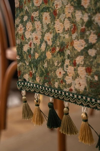 Macro shot of green floral jacquard table runner with multi-color tassel details