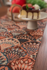 Close-up of bohemian jacquard table runner with orange and blue peacock feather pattern
